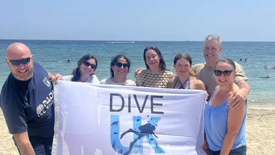 Dive UK group holding a banner on the beach in Hurghada