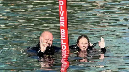 Two divers at the surface beside a red diver-below marker buoy