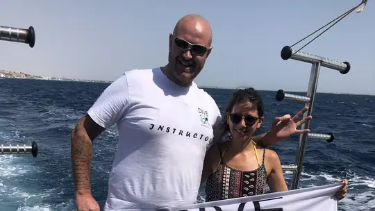 Dive UK instructor and diver holding a banner on a boat