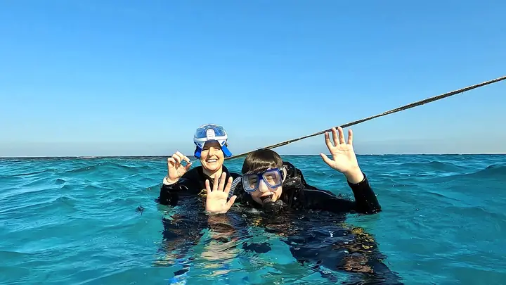 Two divers smiling at the surface in clear blue water