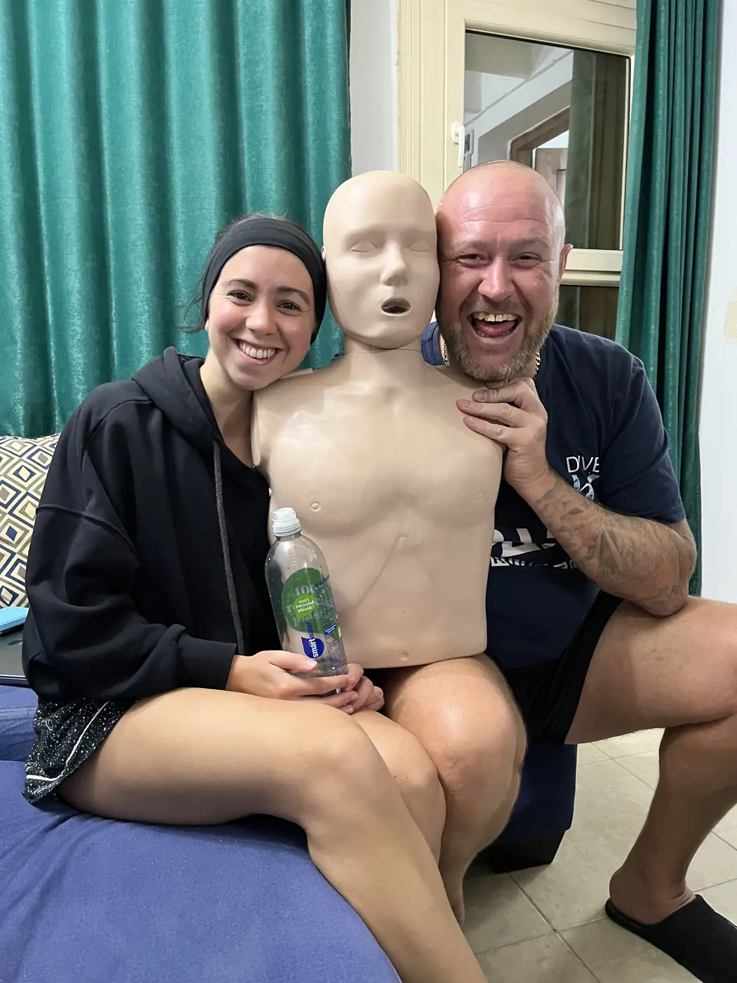 Two people beside a first-aid training mannequin