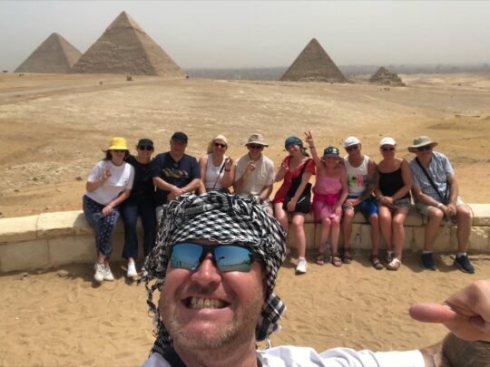Smiling guests in a group selfie with the Giza pyramids in the background