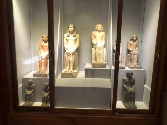 Ancient Egyptian seated statues in a Cairo museum display case