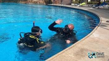 Young learner practising scuba skills with an instructor in a swimming pool