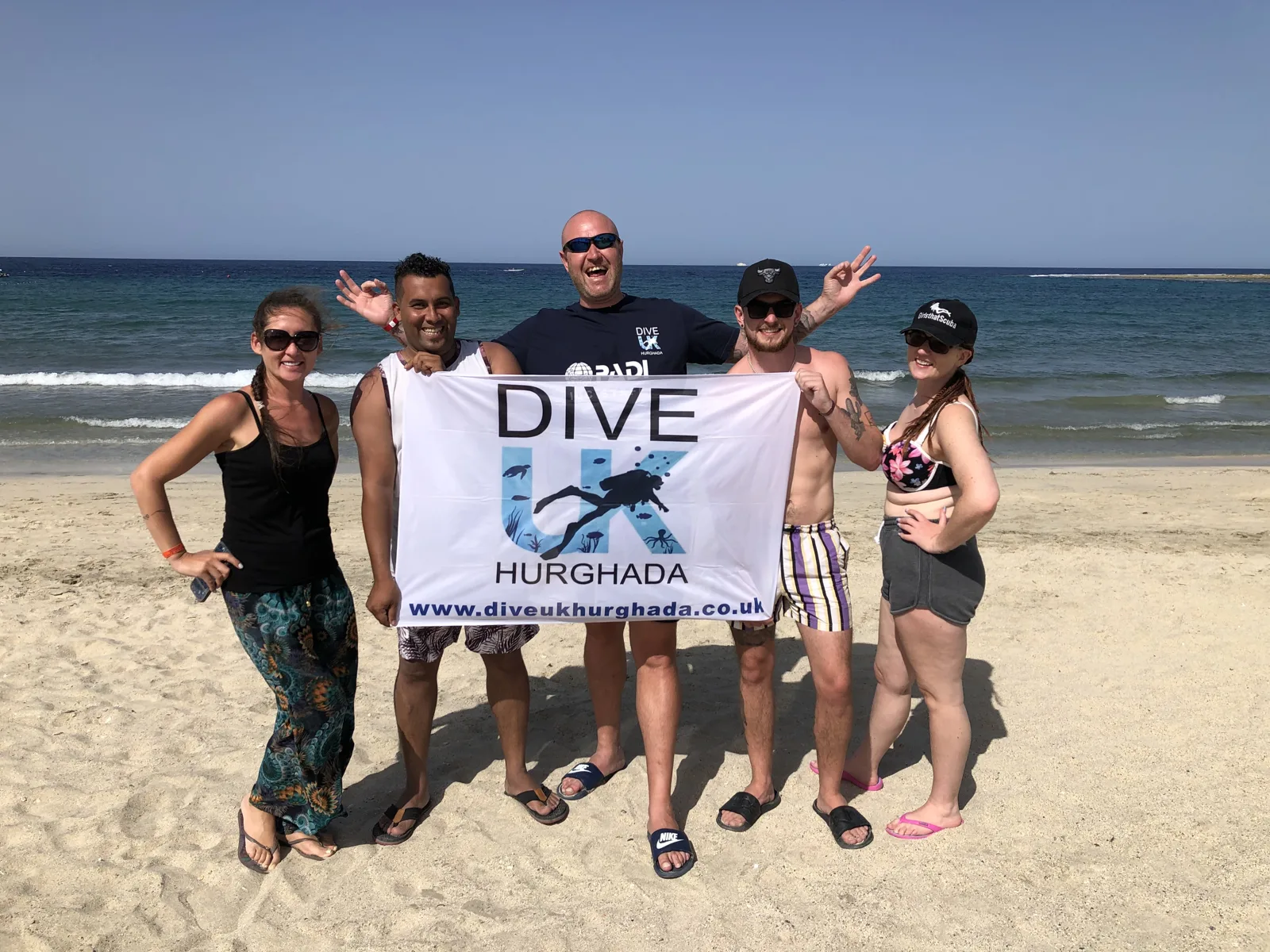 Dive UK Hurghada guests holding a banner on the Red Sea beach