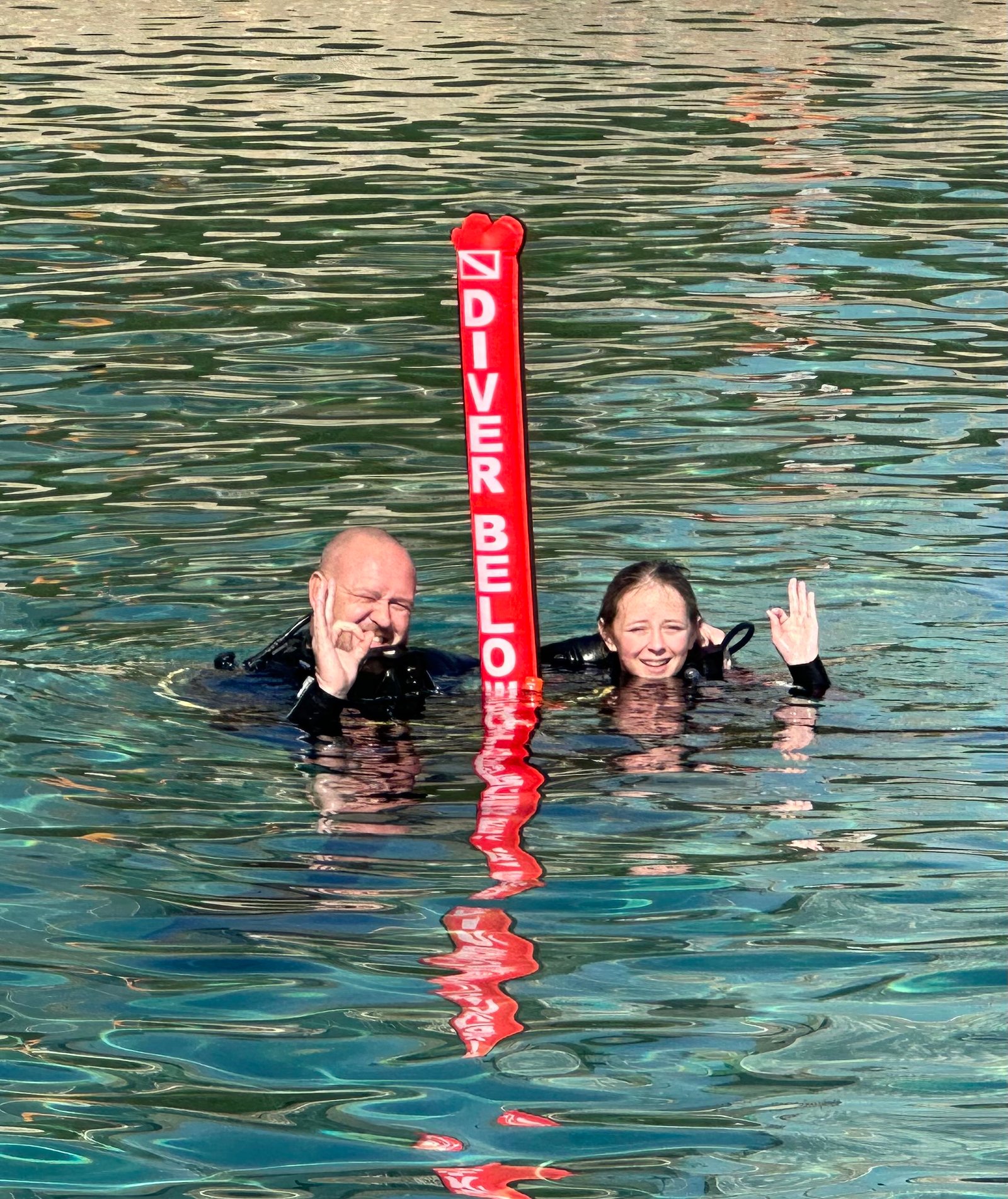 Two divers giving the OK signal beside a surface marker buoy in our PADI Rescue course gallery