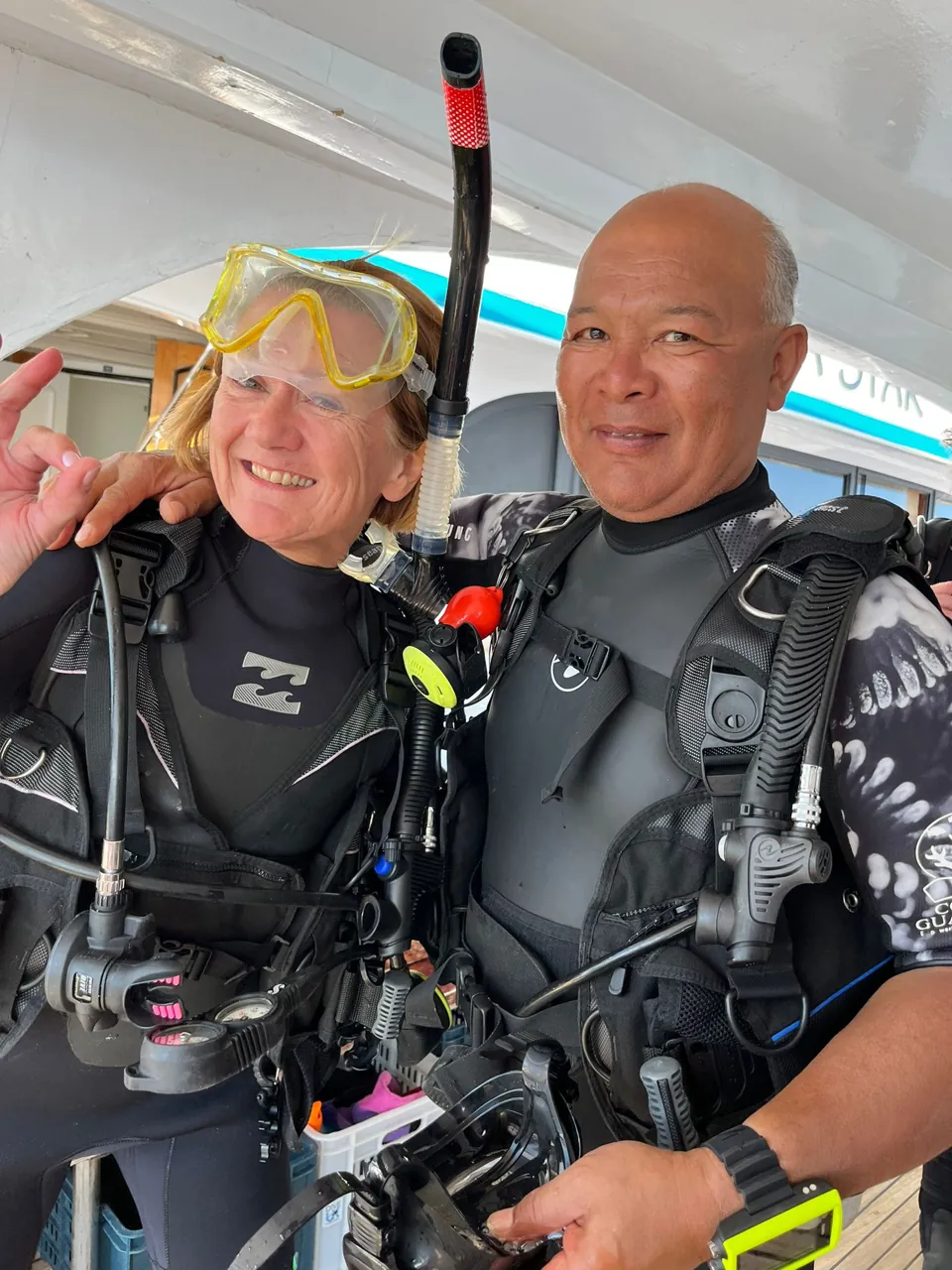 Two people smiling in scuba equipment on a dive boat