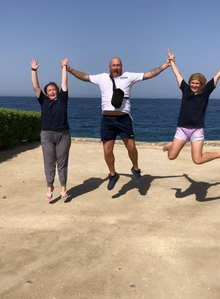Three people celebrating together beside the Red Sea