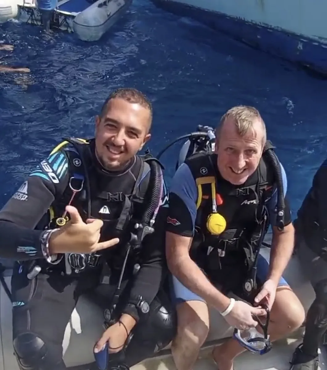 Two divers in scuba equipment sitting on a boat