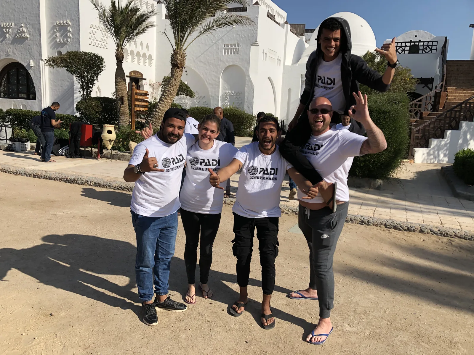 A group wearing PADI Instructor shirts outside a white building