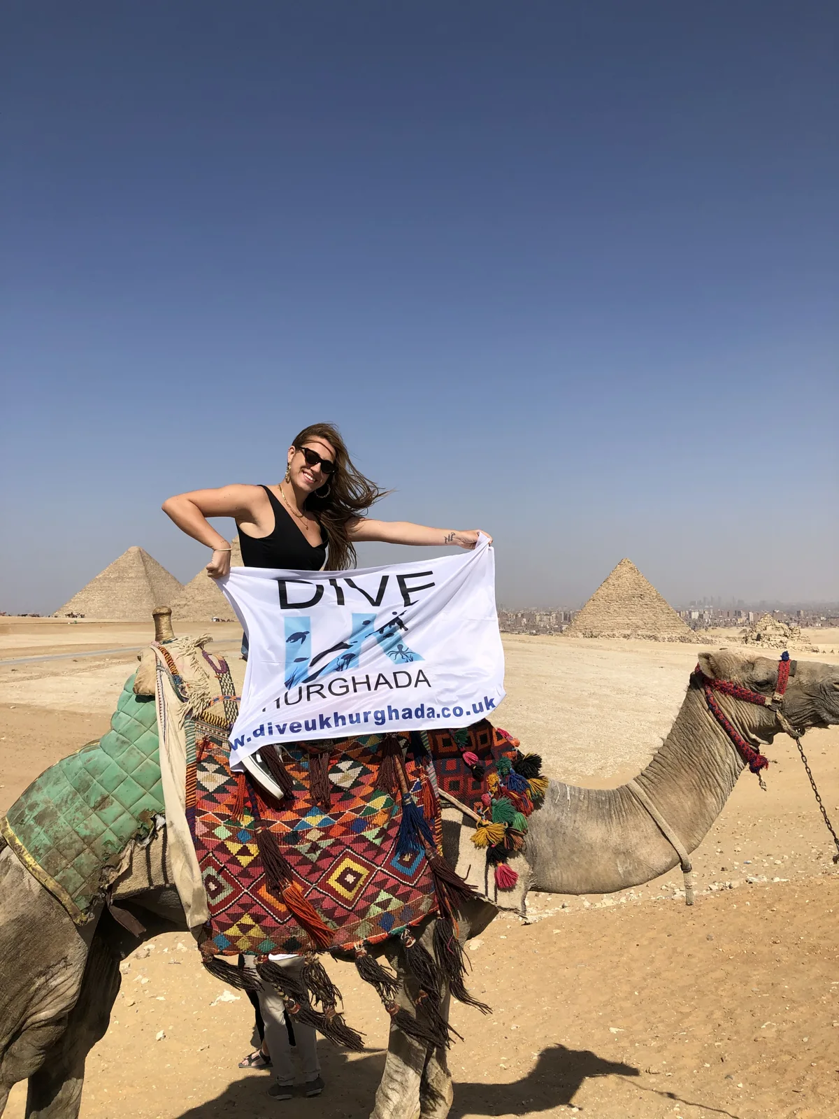 Guest holding the Dive UK Hurghada flag near the pyramids in Giza